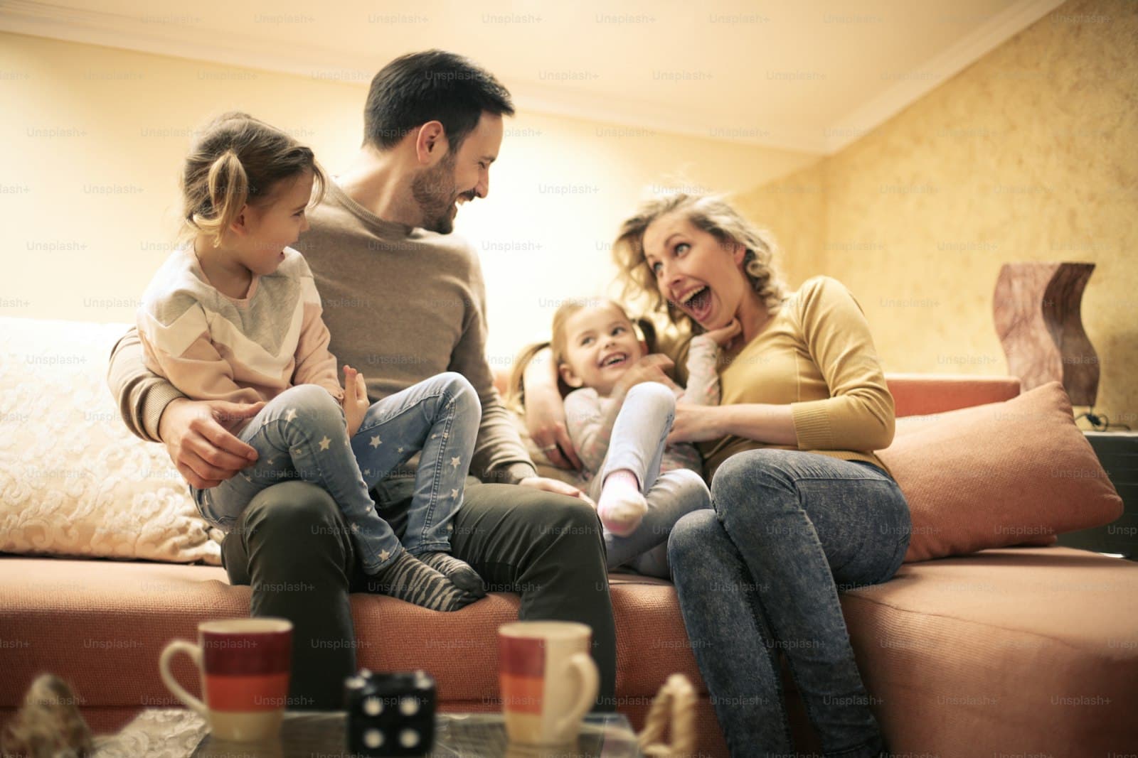Happy family laughing together on couch in warm living room